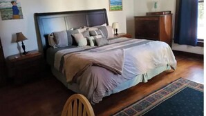 A neatly made bed with a headboard, a bedside table with a lamp, and a small cabinet. - Shawnee Forest In Town Retreat (Harrisburg)