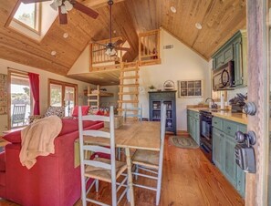 Een gezellig cabin interieur met een slaapkamer op een entresol, een eethoek en een keuken.