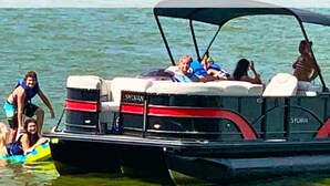 A boat with a covered top, several people on board, and a person in a yellow float in the water. - Amazing rustic cabin with 450' of water frontage on Jackson Lake (Monticello)