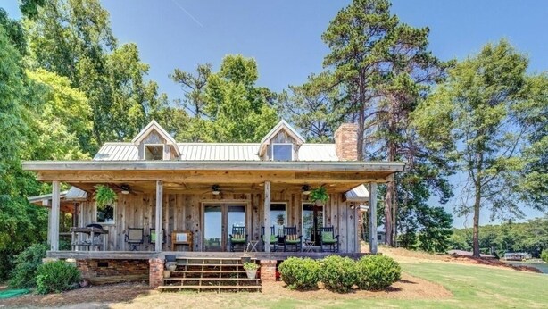 A rustic cabin with a covered porch, multiple windows, and a chimney. - Amazing rustic cabin with 450' of water frontage on Jackson Lake (Monticello)