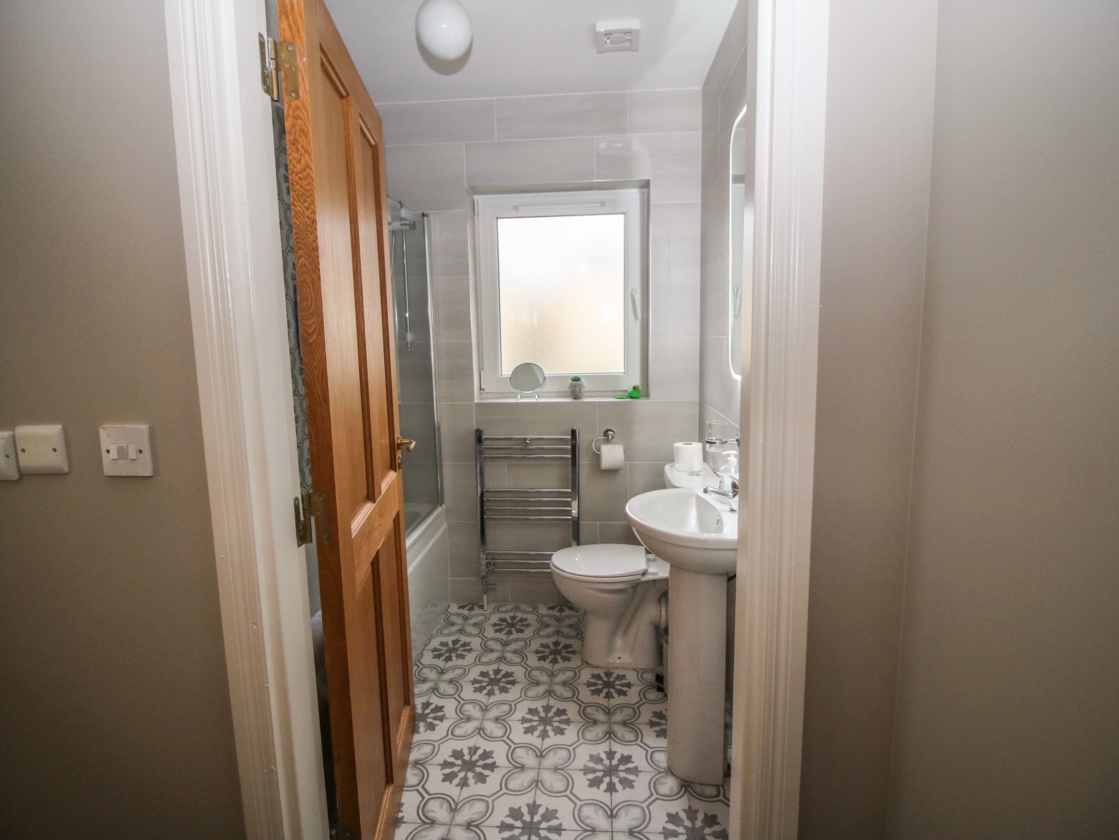 A small bathroom with a toilet, sink, and shower.