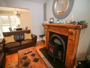 A living room with a fireplace, a sofa, a coffee table, and a dining area visible through a glass door.