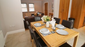 A dining area with a wooden table set for four, surrounded by black chairs. - Pebble Lodge (Kenmare)