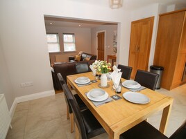 Comedor con una mesa de madera dispuesta para cuatro personas, rodeado de sillas negras.