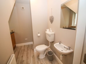 A compact bathroom with a toilet, sink, and a small trash bin.
