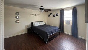 A bedroom with a bed, a ceiling fan, a window with curtains, and wall-mounted lights. - 1 BR - ocean view - unit 2 (Fort Myers Beach)