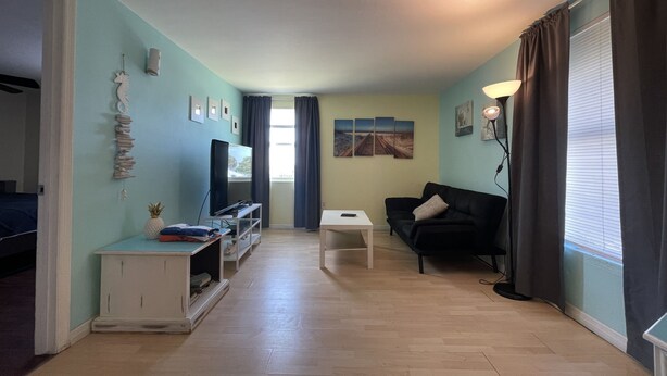 A living room with a TV, a sofa, a coffee table, and a small white cabinet. - 1 BR - ocean view - unit 2 (Fort Myers Beach)