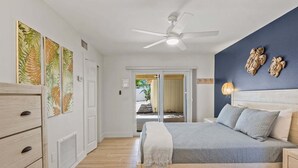 Une chambre avec un lit, un ventilateur de plafond et une vue sur un espace extérieur.