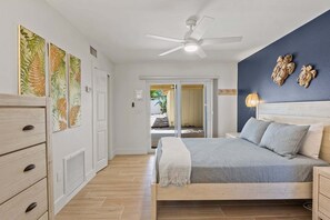 Una camera da letto con un letto, una ventola a soffitto e vista su uno spazio esterno.
