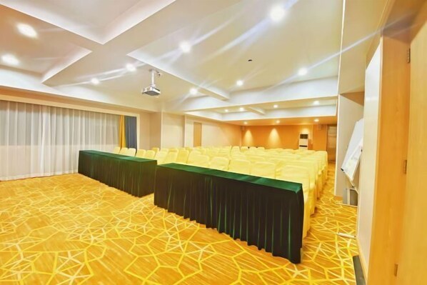 A conference room with a long table, rows of chairs, and a patterned carpet.