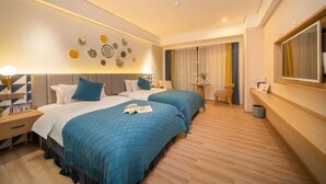 Quarto de hotel com duas camas, uma mesinha, uma cadeira, mesa de cabeceira e um espelho grande.
