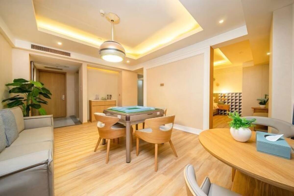 A modern living room with a wooden dining table, a sofa, and a ceiling light fixture.