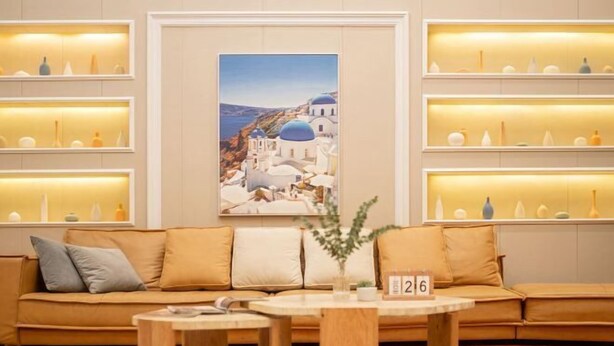 Um hall de hotel moderno com um sofá, uma mesa de centro e prateleiras com objetos decorativos.
