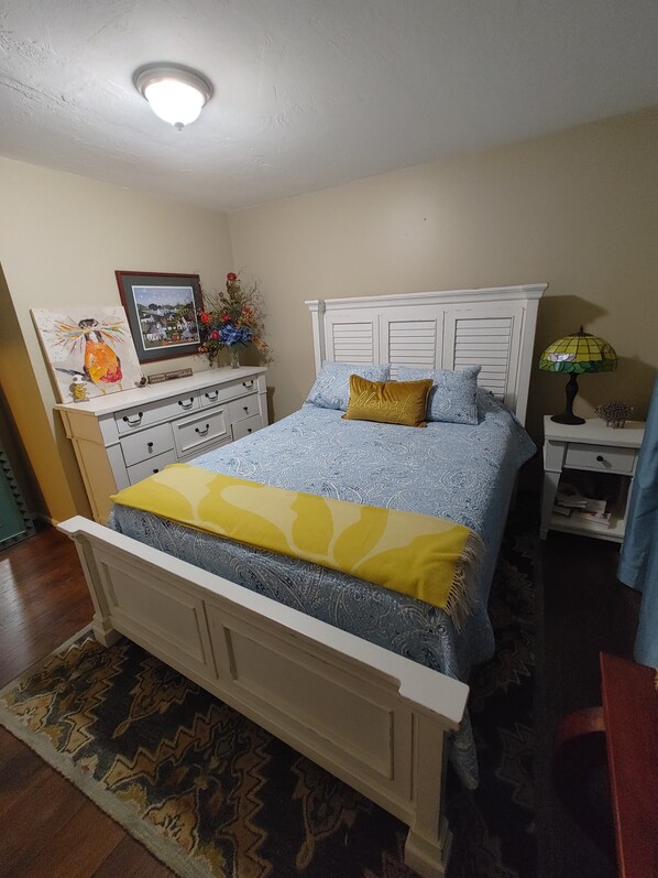 A bedroom with a bed, a dresser, a nightstand, and a ceiling light.