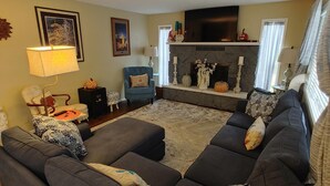 A living room with a sectional sofa, a fireplace, and a television.