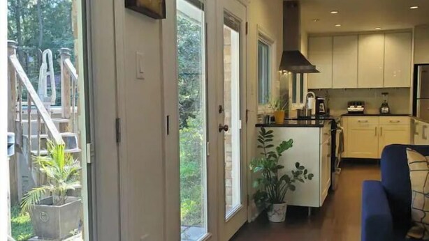 A modern kitchen with wooden cabinets, a central island, and a large window. - Beautiful Island Home (Savannah)