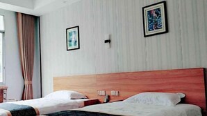 A hotel room with two beds, wooden headboards, and framed artwork on the walls. - Jinjiang Zhixing Hotel (Fengshan)