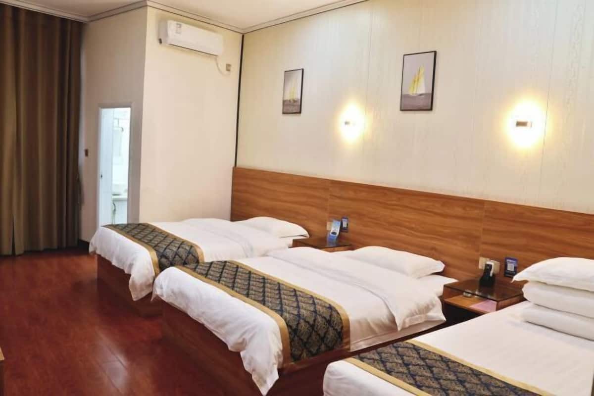 A hotel room with two beds, a wooden headboard, wall-mounted lights, and a door to the left.
