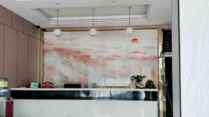 A reception desk with a marble top, a large abstract painting above it, and a ceiling with recessed lighting. - Jinjiang Zhixing Hotel (Fengshan)
