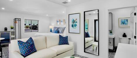 A modern living room with a sofa, a coffee table, and a large mirror.