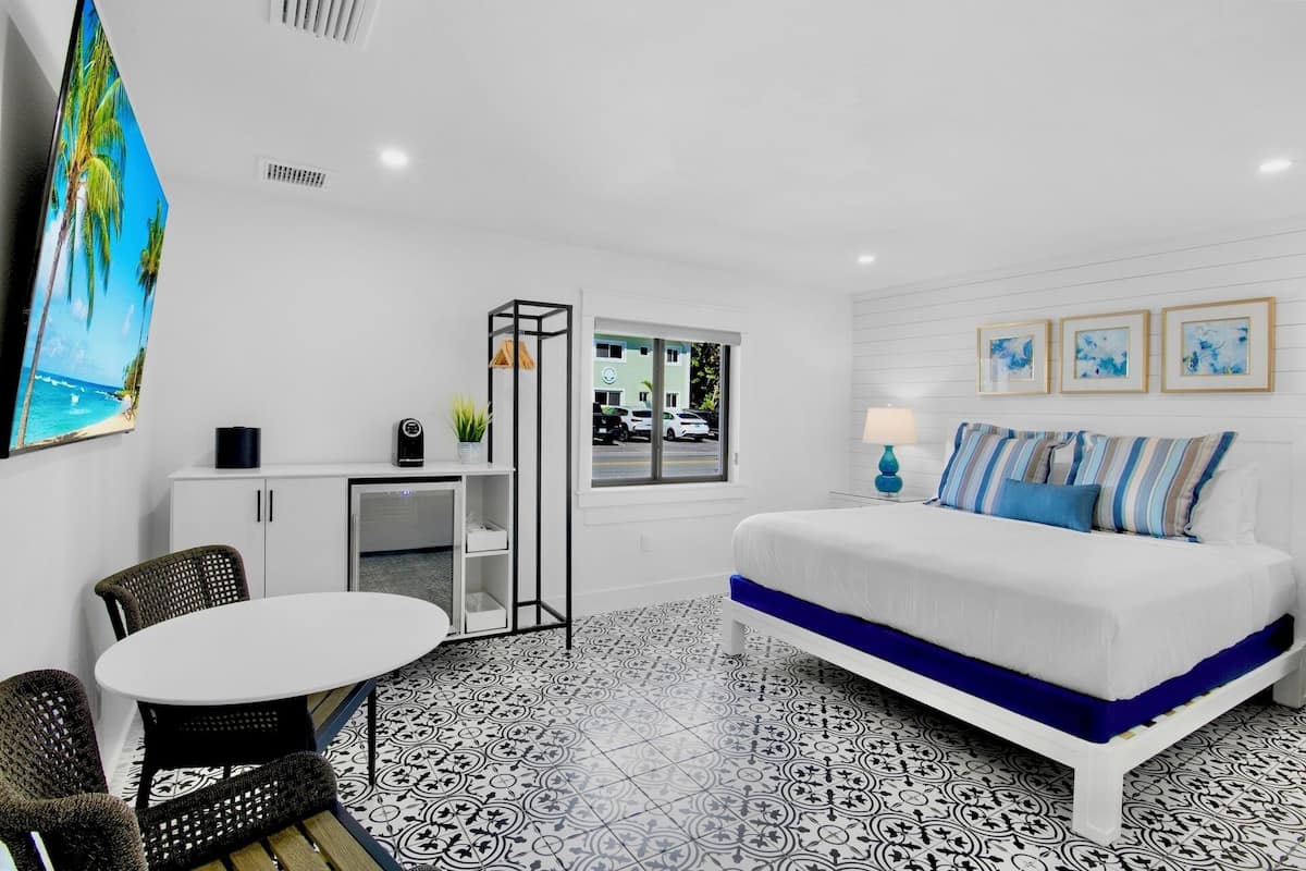 Una habitación de hotel moderna con una cama, un escritorio, una silla y un ventanal con vista a la calle.