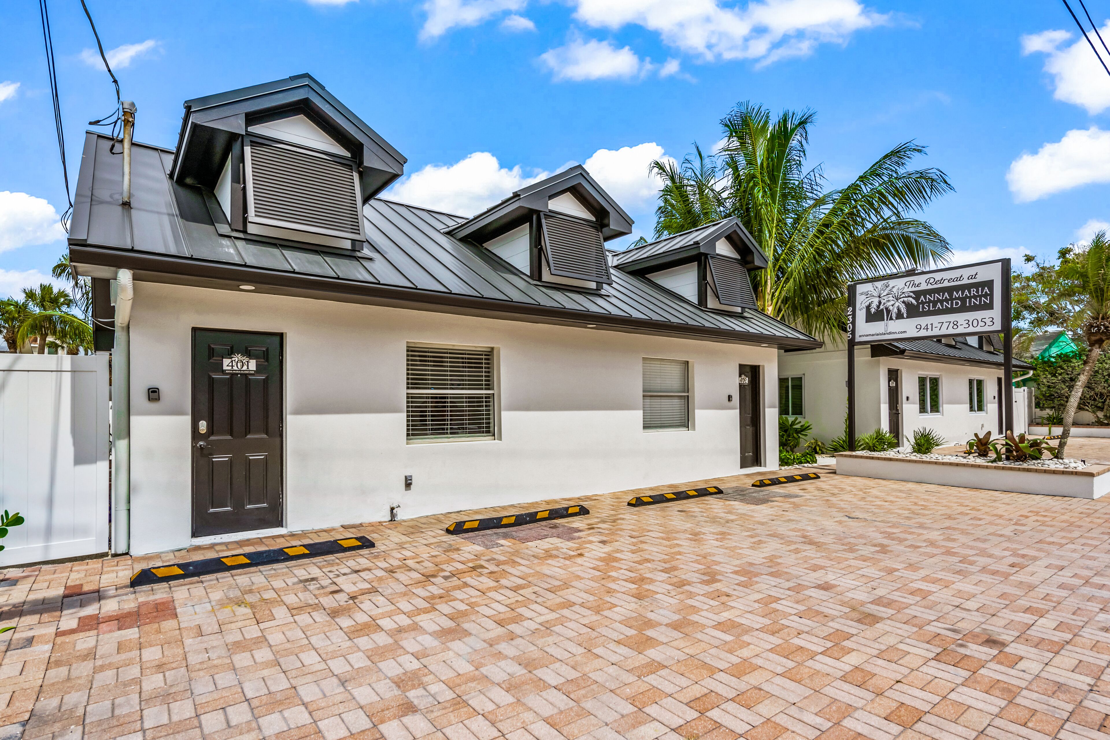 A modern building with a flat roof, a black door, and a sign for Anna Maria Island Inn.