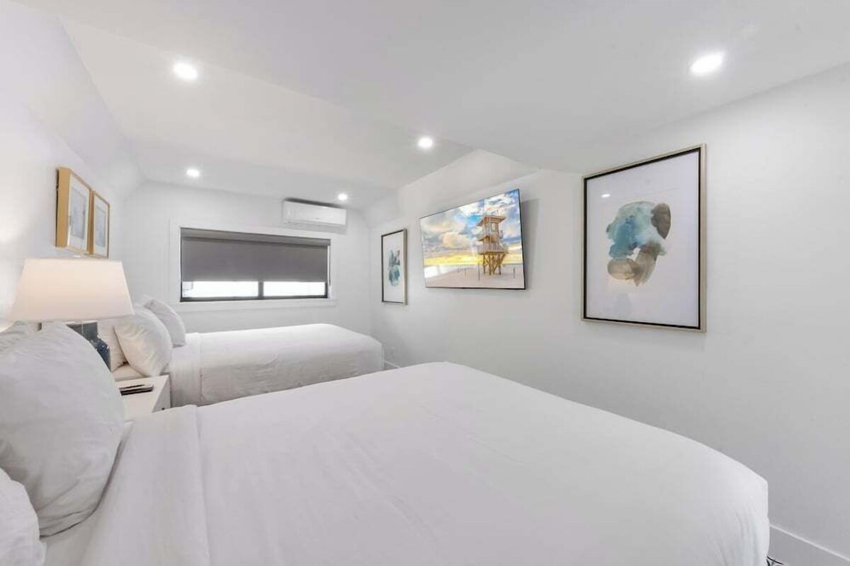 Een slaapkamer met twee bedden, een raam en kunstwerken aan de muur.