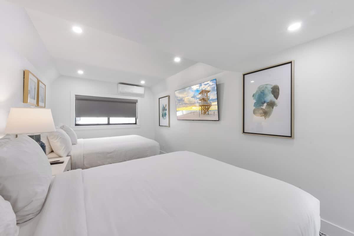 Habitación de hotel con dos camas, una ventana y obras de arte en las paredes.