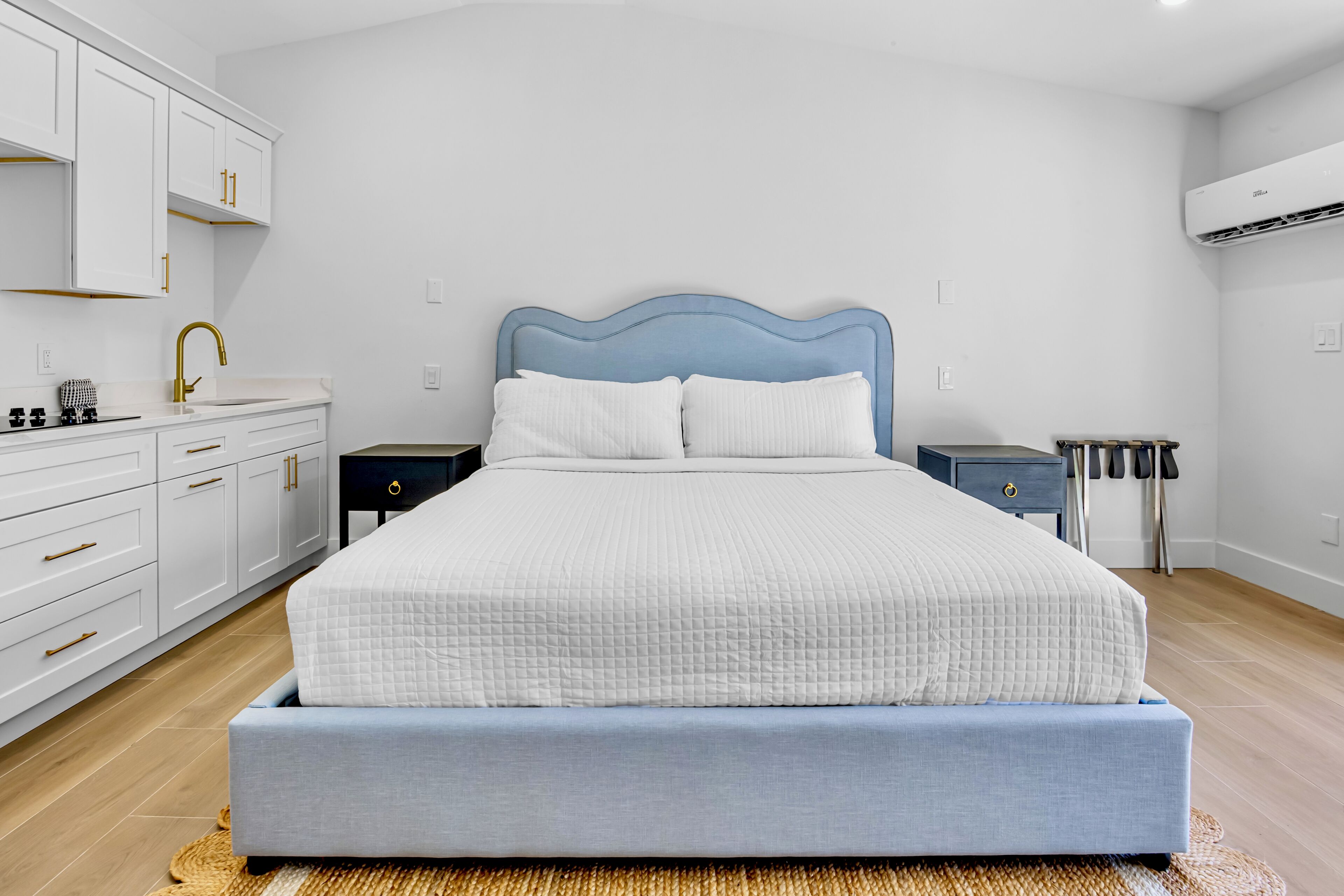 A bedroom with a bed, a nightstand, a dresser, and an air conditioning unit.