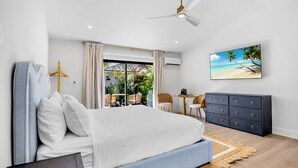 Un dormitorio con cama, escritorio, silla, armario y vistas al exterior.