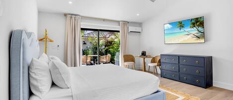 A bedroom with a bed, a desk, a chair, a wardrobe, and a view of the outdoors.