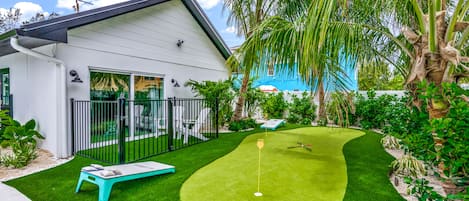 A modern house with a well-maintained lawn and a golf putting area.