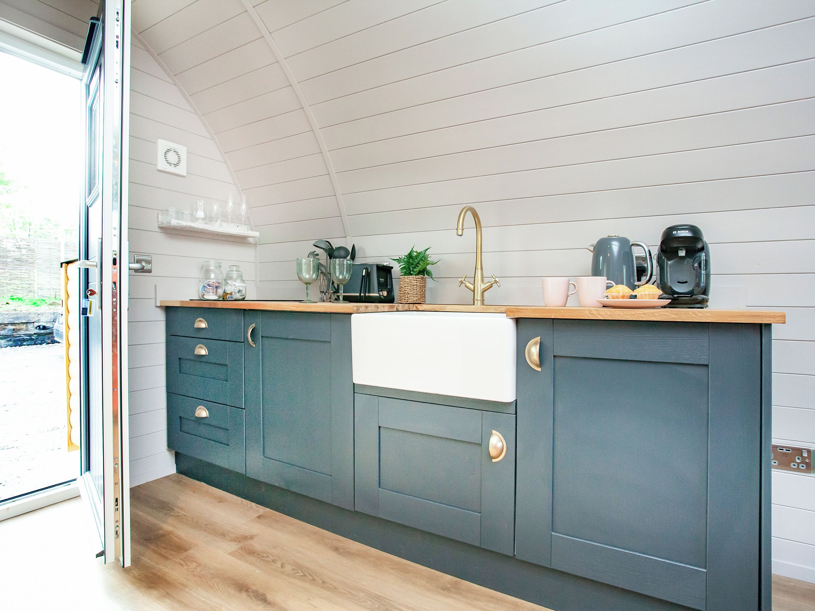 A modern kitchen with a wooden countertop, a sink, and a Bosch coffee maker.