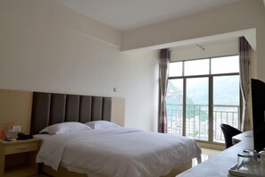 Ein Hotelzimmer mit einem großen Bett, einem Schreibtisch und einem Fenster mit Vorhängen.