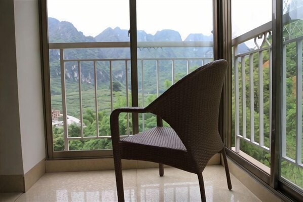 A chair in a room with a large window overlooking a mountainous landscape.