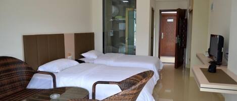 A hotel room with a bed, two chairs, a small table, a TV, and a trash bin.