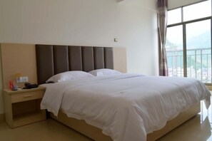 Ein Hotelzimmer mit einem großen Bett, einem Nachttisch mit Telefon und einem Fenster mit Bergblick.