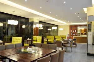 Un comedor moderno con una mesa de vidrio, sillas tapizadas en amarillo e iluminación colgante.