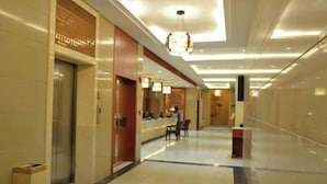 A hotel lobby with a reception desk, a seating area, and an elevator. - Bama Shanshui Bipoyuan Hotel (Bama)