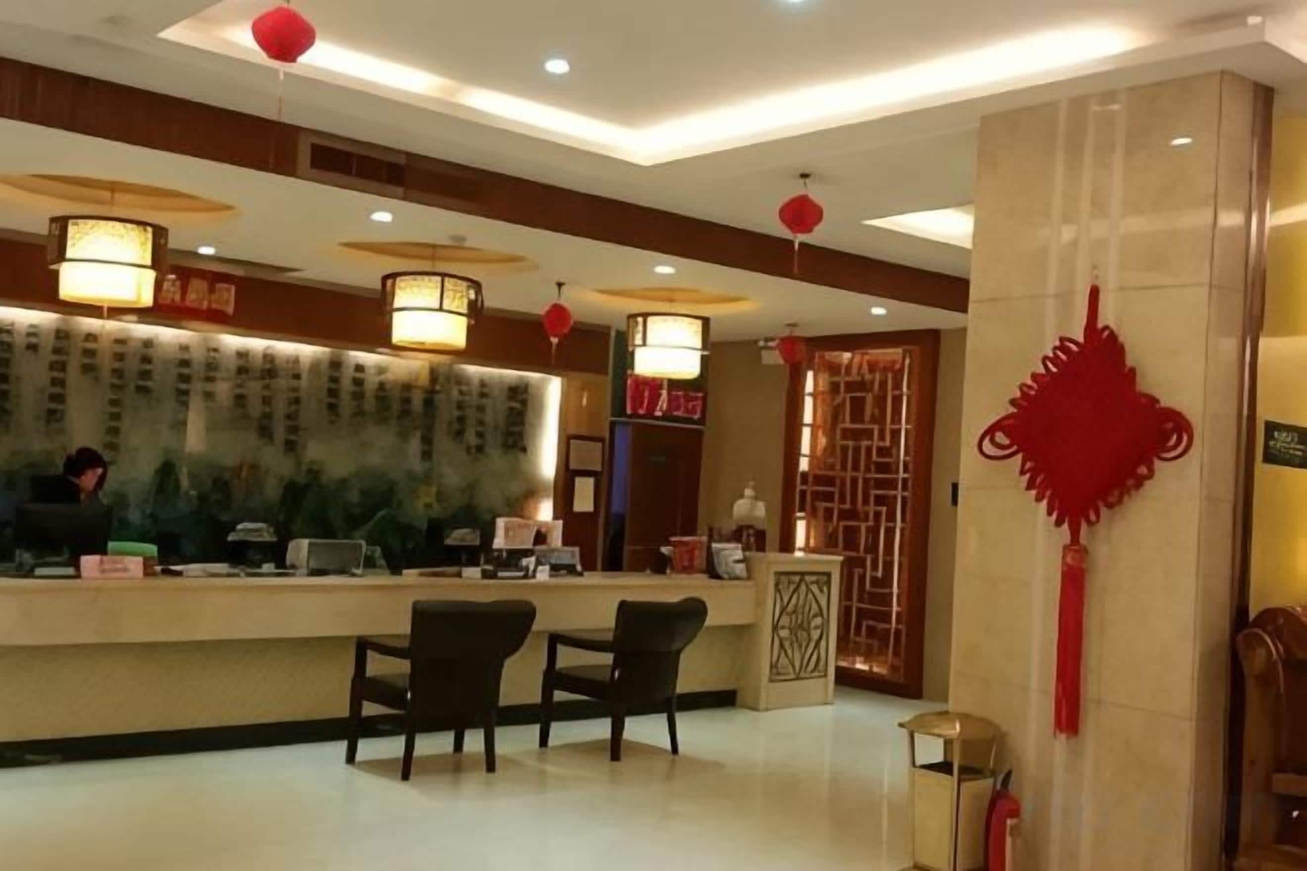 A hotel reception area with a counter, chairs, and a decorative wall.