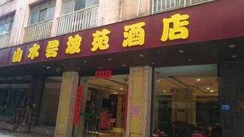 A hotel entrance with a maroon facade and yellow signage.