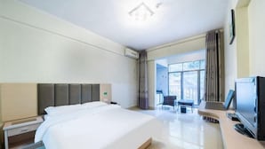A hotel room with a large bed, a desk with a flat-screen TV, and a view of the outdoors through a large window. - Bama Shanshui Bipoyuan Hotel (Bama)