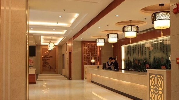 A hotel reception area with a long corridor, reception desk, and decorative lighting fixtures. - Bama Shanshui Bipoyuan Hotel (Bama)
