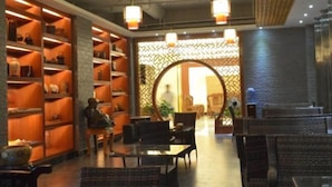 A lobby with a reception desk, seating area, and a wall with shelves displaying items. - Bama Shanshui Bipoyuan Hotel (Bama)