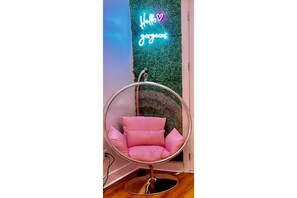 Relax in a stylish chair with a comfortable cushion, positioned against a unique wall featuring a vibrant message.