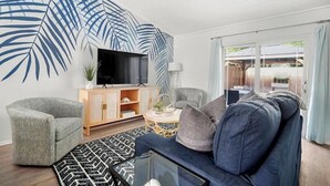 A living room with a TV, sofa, armchairs, and a cabinet. - Beach Getaway - Team Joseph Ellen (Atlantic Beach)