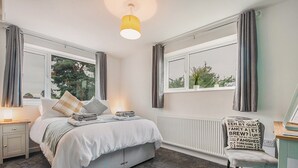 A bedroom with a bed, bedside tables, a chair, a window with curtains, and a radiator. - 1 bedroom accommodation in Acomb, near York (Acomb, near York)