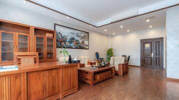 Una habitación amplia con un mostrador de recepción de madera, un cuadro grande en la pared y una zona de estar con sofá y sillones.