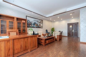 Una habitación amplia con un mostrador de recepción de madera, un cuadro grande en la pared y una zona de estar con sofá y sillones.