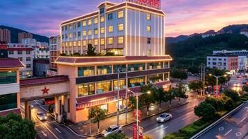 A multi-story hotel with a prominent red sign, multiple floors, and a well-lit facade.